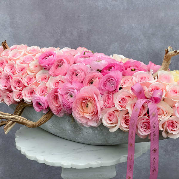 Pink rose and ranunculus arrangement in a gray bowl with ribbon
