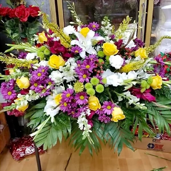 Large mixed floral spray with roses, lilies, and purple daisies