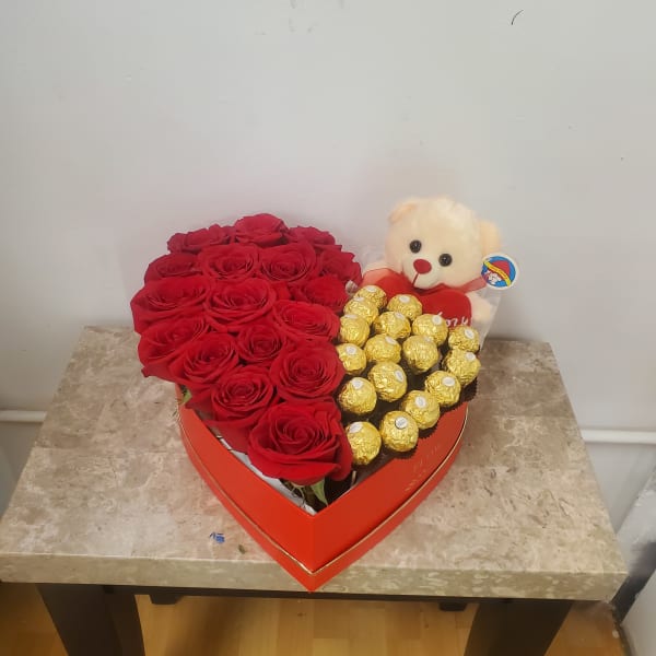 Heart-shaped box with red roses, chocolates, and a teddy bear