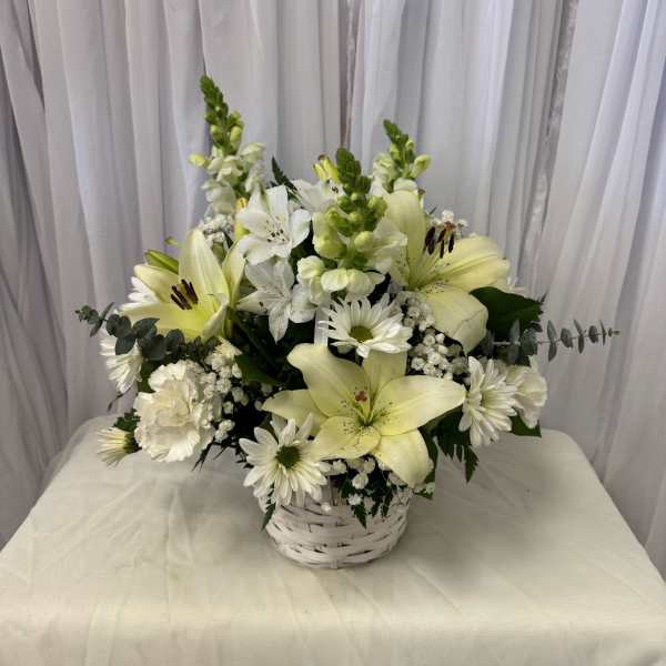 White lilies and daisies arranged in a white basket