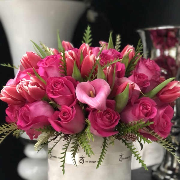 Pink roses and calla lilies arranged in a white hat box