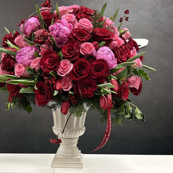 Red and pink rose bouquet in a white pedestal vase