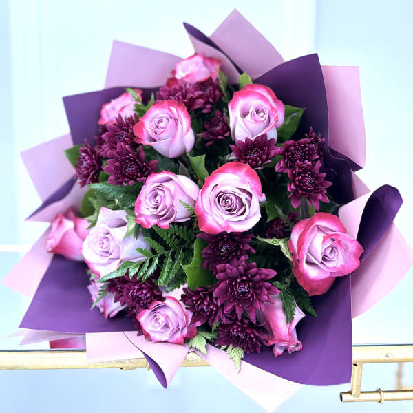 Bouquet of pink roses and dark purple chrysanthemums wrapped in purple paper