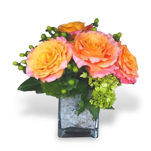 Orange and pink roses in a square glass vase