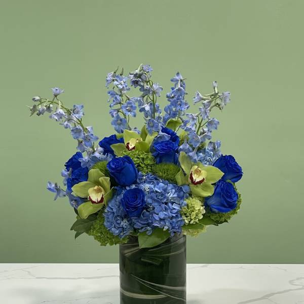 Blue and green floral arrangement in a glass vase