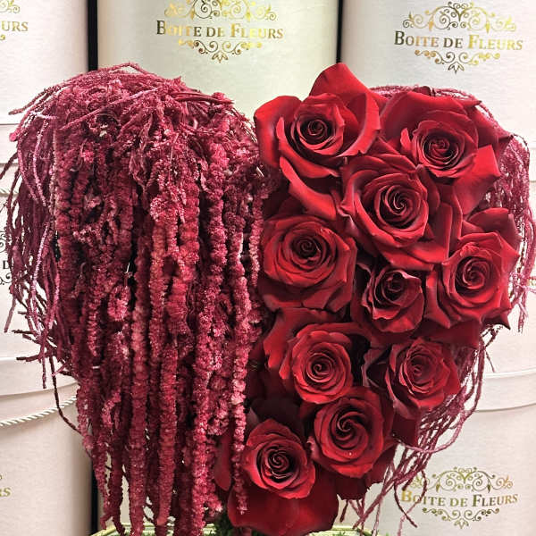 Red roses arranged in a heart shape with burgundy hanging accents