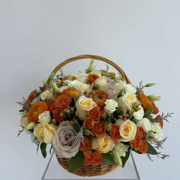 Basket of orange, cream, and white roses with ranunculus