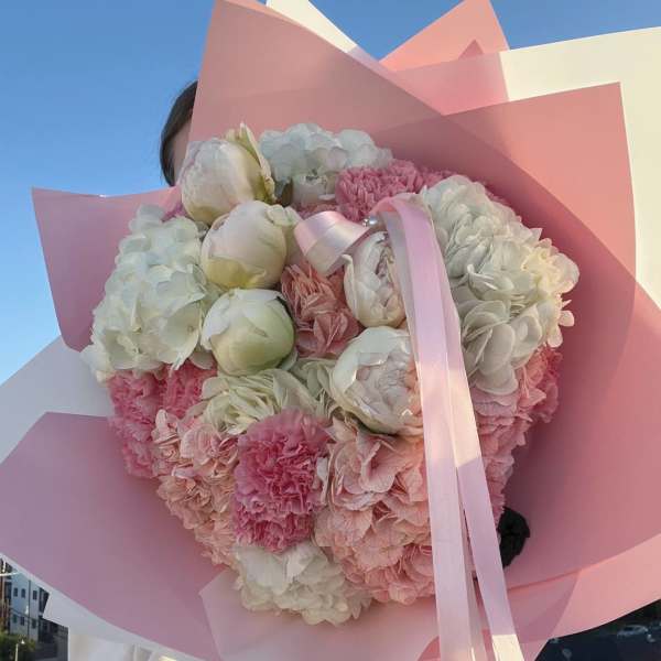 Pink and white bouquet with peonies and hydrangeas wrapped in pastel paper