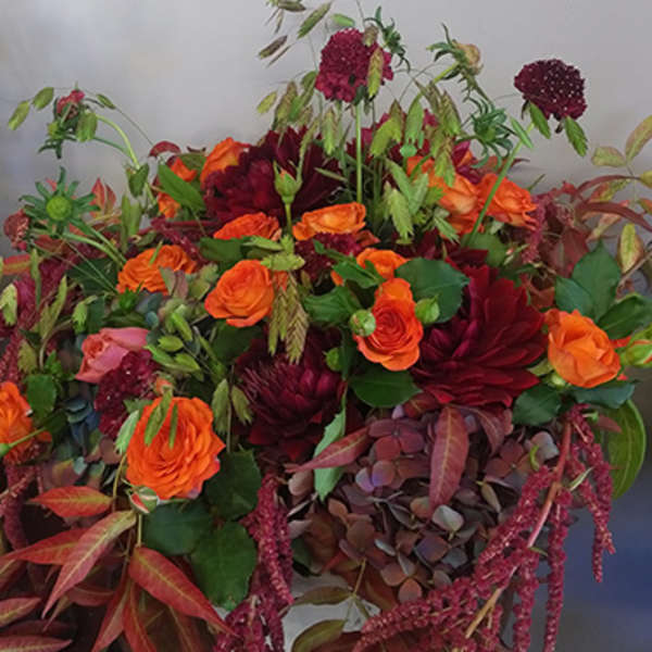 Large bouquet of orange and burgundy flowers with mixed foliage