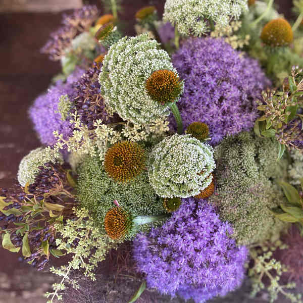 Purple and white floral bouquet with round orange-centered blooms