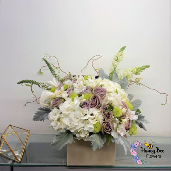 White and lavender floral arrangement in a square box