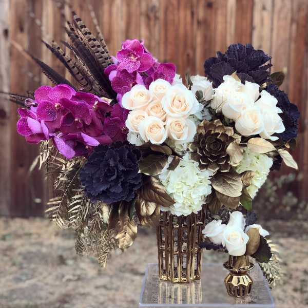 Bouquet of white roses and purple orchids in a gold vase