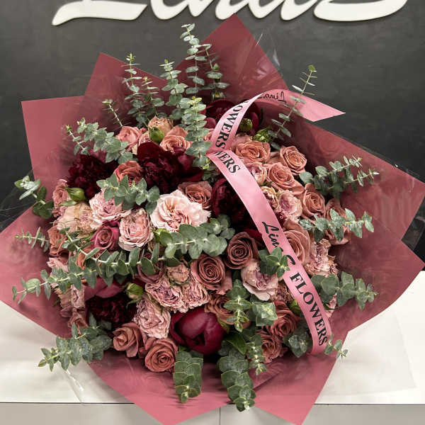 Bouquet of pink roses and dark red flowers wrapped in pink paper