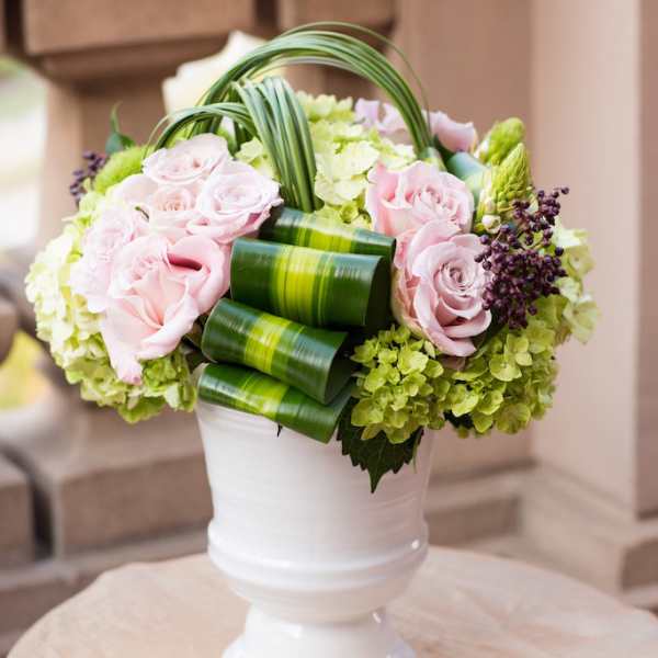 Pink roses and green hydrangeas arranged in a white urn