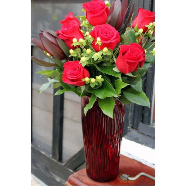 Red roses arranged in a tall red glass vase