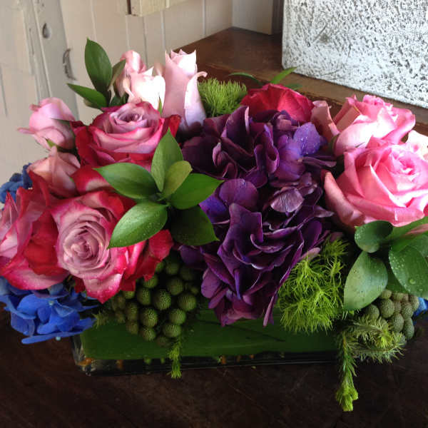 Pink and purple rose arrangement in a low rectangular vase