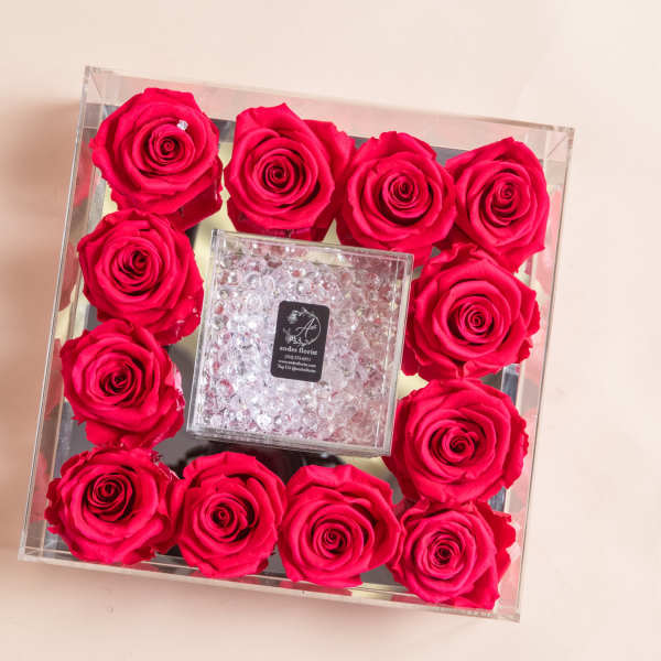 Square clear box filled with hot pink roses around a crystal center