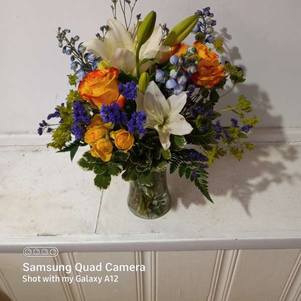 Bouquet of orange roses and white lilies in a glass vase