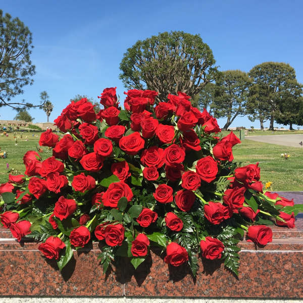 Large bouquet of red roses arranged on a stone memorial ledge