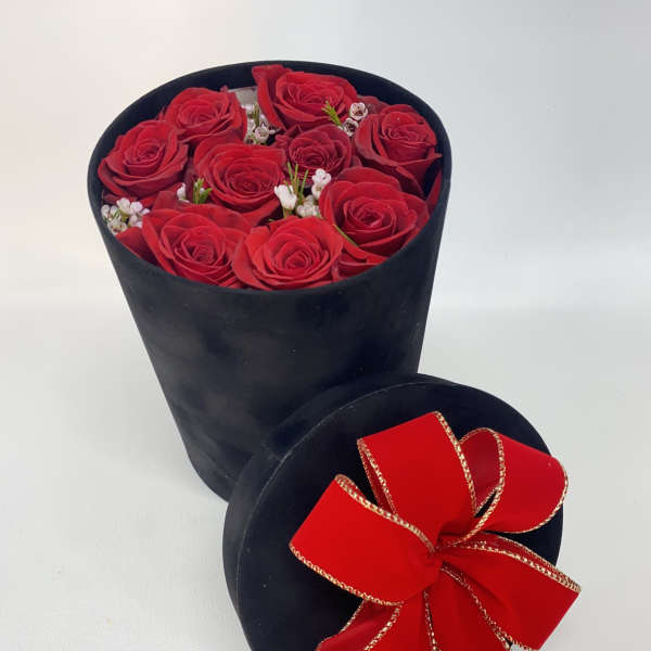 Red roses in a black round box with a red ribbon bow