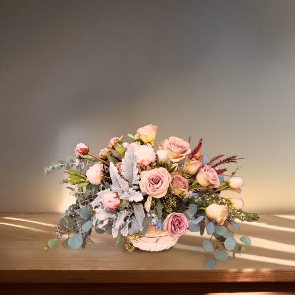 Low bouquet of pale pink roses in a white vase