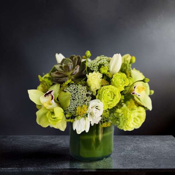 Green and white floral arrangement in a glass vase