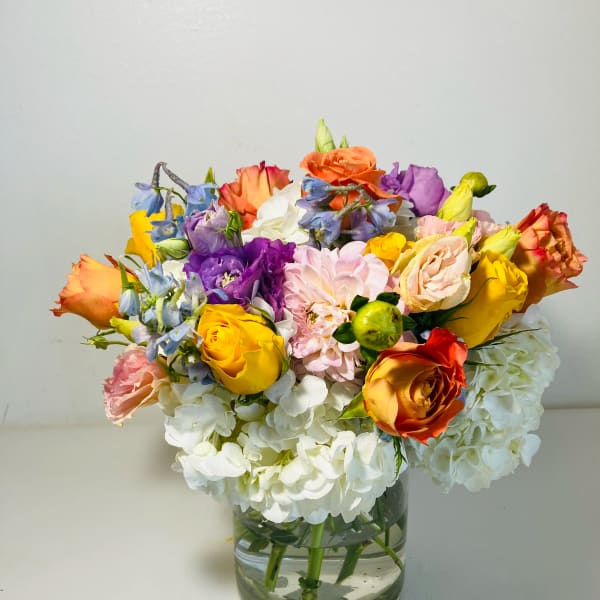 Colorful mixed bouquet in a clear glass vase with white hydrangeas