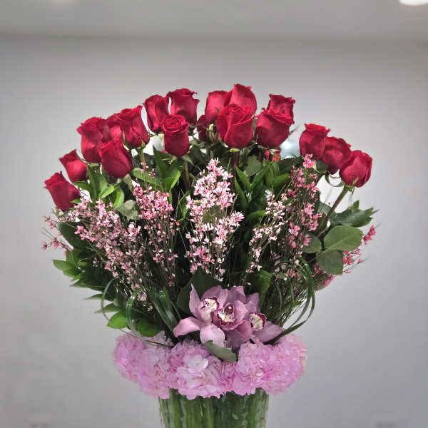 Red roses and pink flowers arranged in a clear glass vase