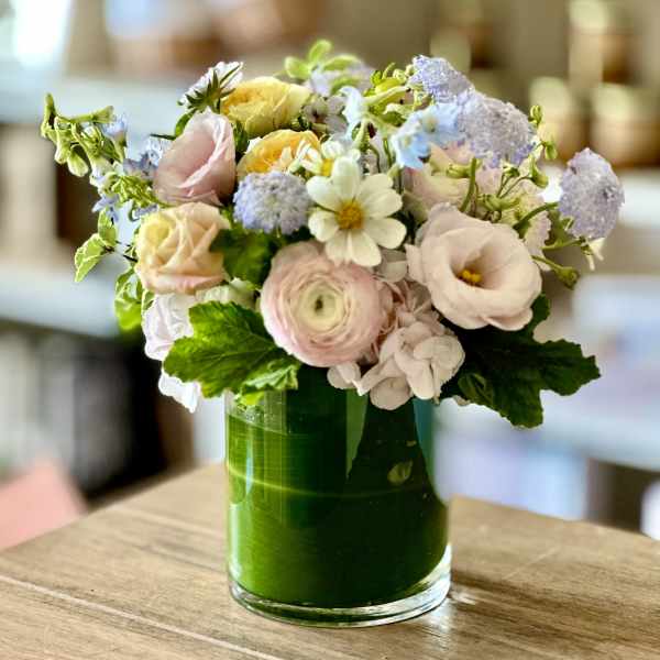 Pastel mixed flower arrangement in a green glass vase