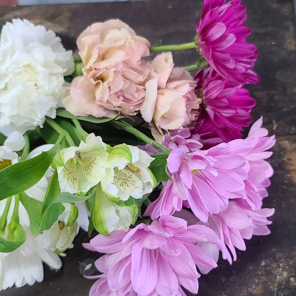Assorted pink, white, and purple flowers laid on a dark surface