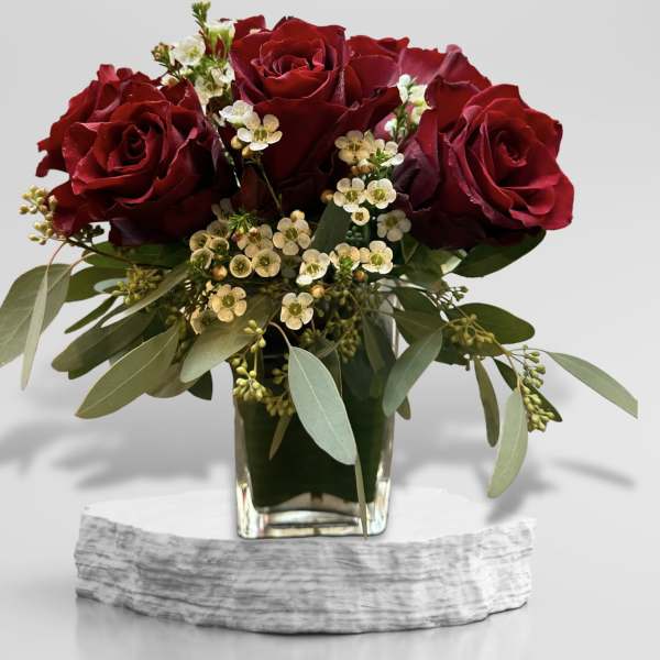Red roses in a glass vase with small white filler flowers