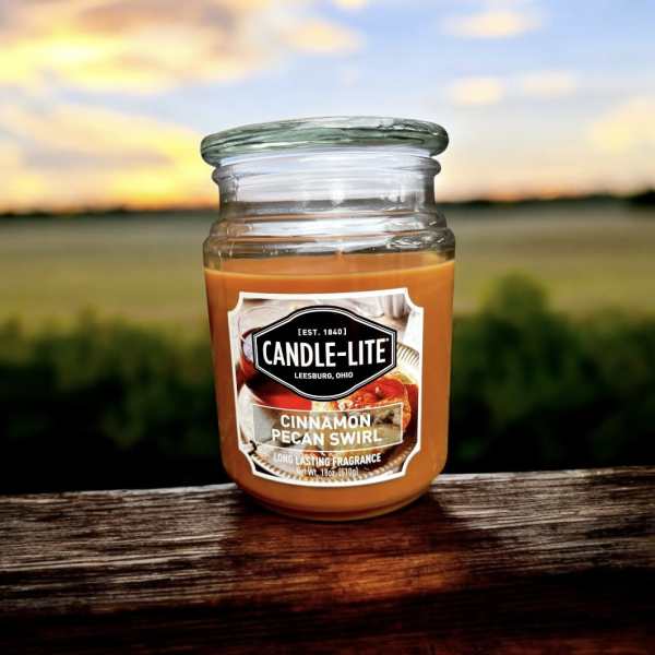 Jar candle labeled Cinnamon Pecan Swirl on a wooden surface
