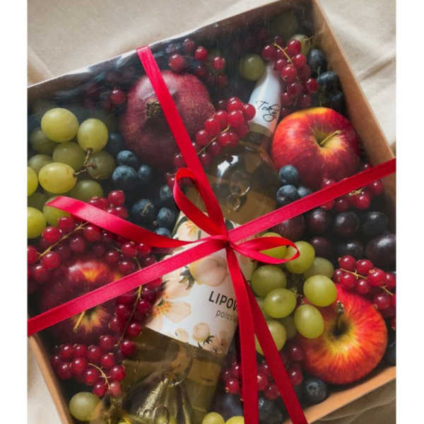 Gift box with fruit and a bottle tied with a red ribbon