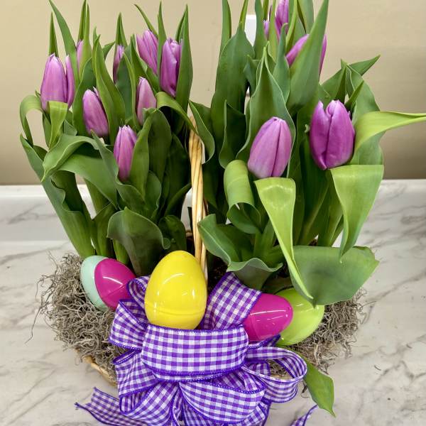Purple tulips in a basket with colorful Easter eggs and a gingham ribbon