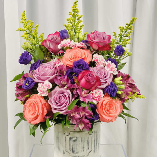Mixed bouquet of roses, alstroemeria, and carnations in a white container