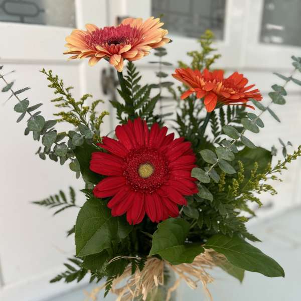 Bouquet of red and orange gerbera daisies in a glass vase