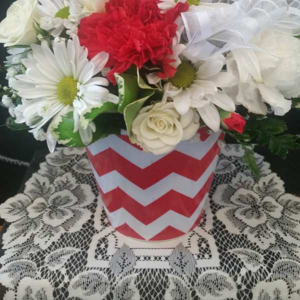 Bouquet of white daisies, red carnations, and white roses in a chevron vase with a heart topper