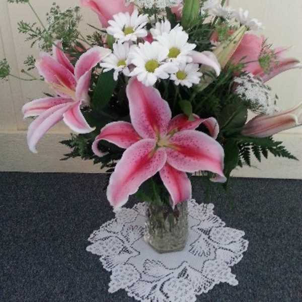 Pink lilies and white daisies arranged in a glass vase