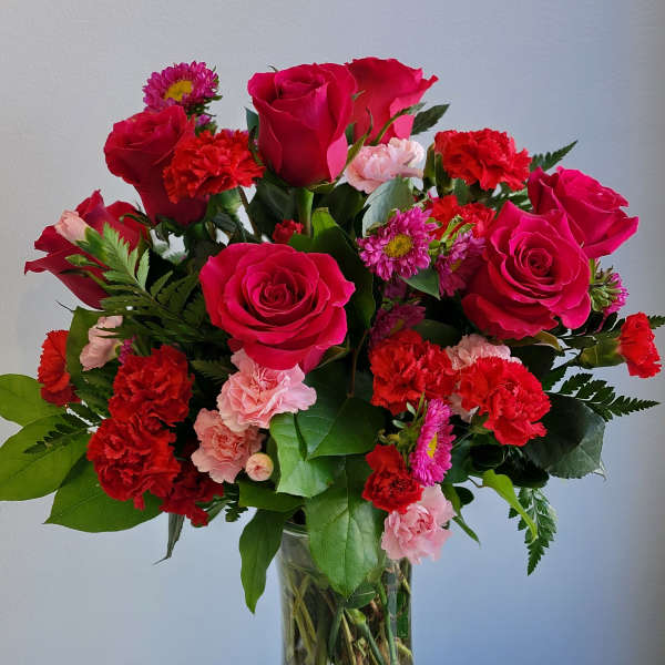 Bouquet of hot pink roses and red carnations in a clear glass vase