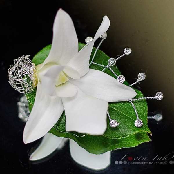 White orchid corsage with green leaf and silver bead accents