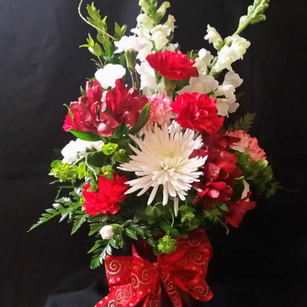 Red and white mixed flower arrangement in a red ribboned container