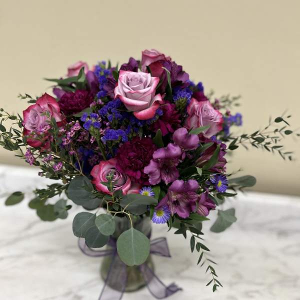 Bouquet of pink and purple flowers in a glass vase with a ribbon