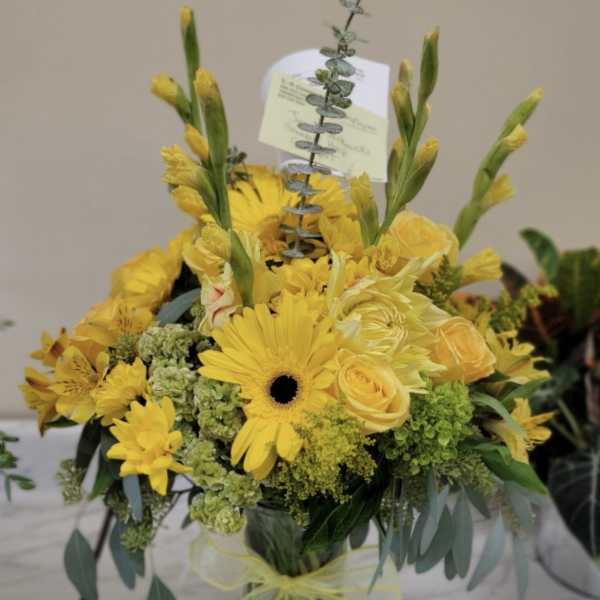 Yellow bouquet in a glass vase with gerbera daisies and roses