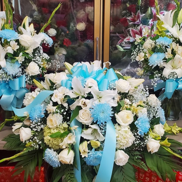 White lily and rose arrangements with blue ribbon bows in glass vases
