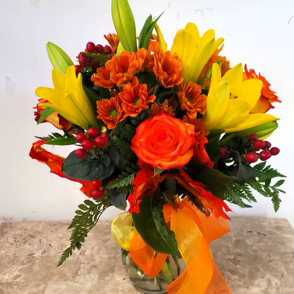 Orange and yellow bouquet in a glass vase with ribbon