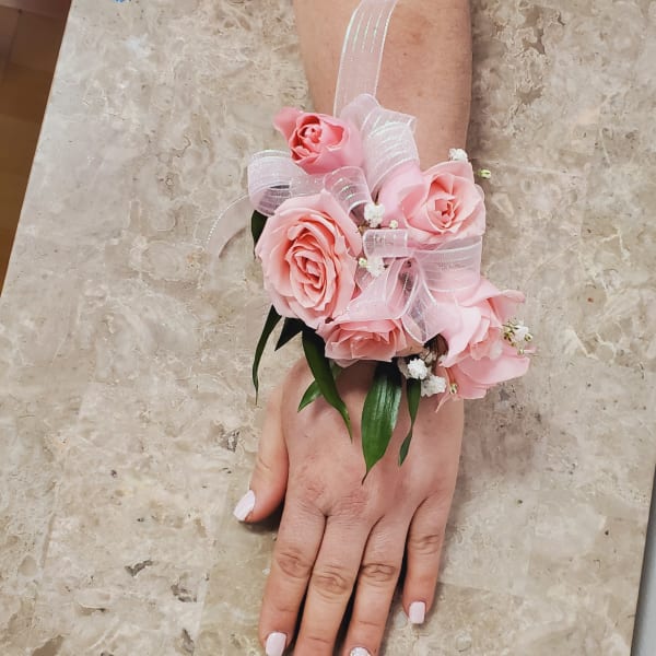 Pink rose wrist corsage with sheer ribbon on a person's wrist