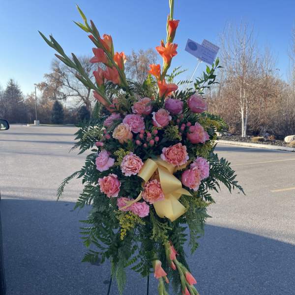 Standing floral spray with pink roses and orange gladiolus on an easel