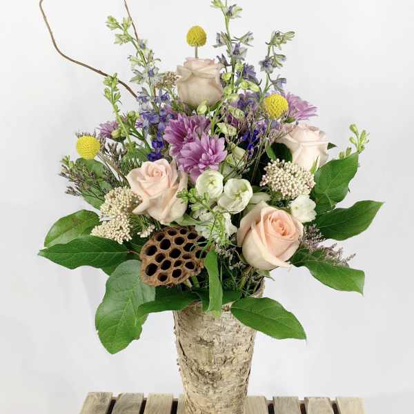 Mixed bouquet in a birch bark vase with pale roses and purple flowers