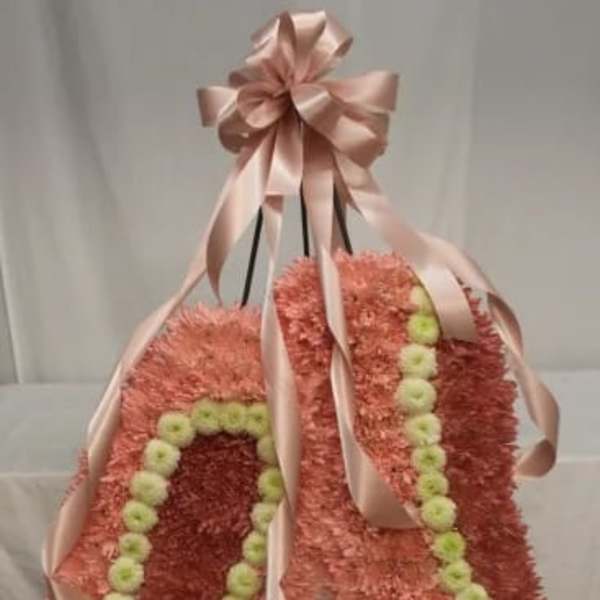 Pink floral standing spray with pale ribbon and green accents