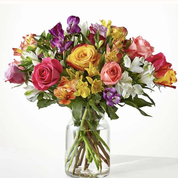 Mixed bouquet of colorful roses and alstroemeria in a clear glass vase